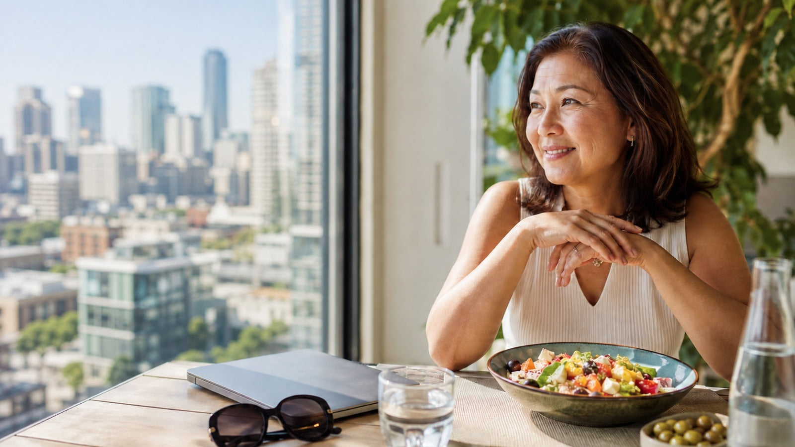 Confident woman over 40 enjoying a colorful Mediterranean meal in natural daylight, representing nutrition, UV protection and healthy vision aging.